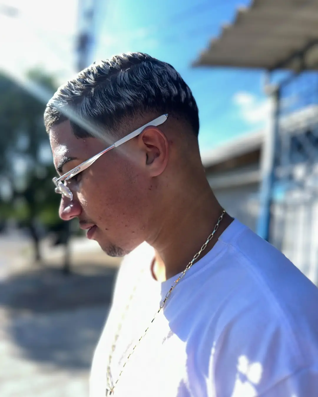 Cliente de perfil com corte texturizado com luzes e degradê, feito na Xina Cortes